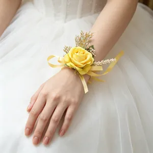 Detailed view of yellow artificial rose wrist flower with ribbon and green foliage