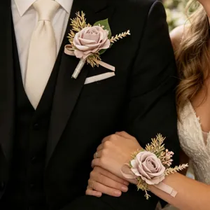 Close-up of matching wedding rose boutonniere and wrist corsage set with gold leaf accents.