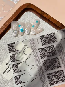 Detailed shot of vintage French lace press-on nails and black white DIY nail sticker sheet.