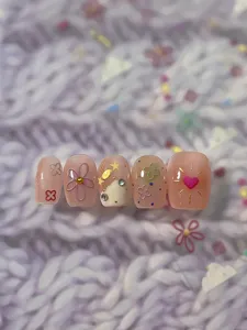 Vista detallada de uñas postizas pastel de primavera con bonitos diseños florales y de corazones.