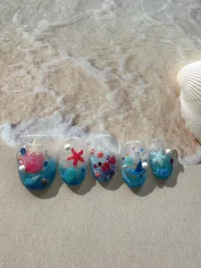 Close-up detail of summer ocean style false nail art set with 3D relief shell and starfish.