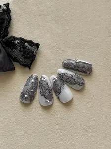 Detailed shot of Japanese style black lace press-on nails with 3D embossed floral patterns and rhinestones.