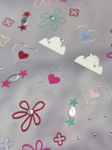 Detalles en primer plano de pegatinas de uñas coloridas con corazones, estrellas y flores.