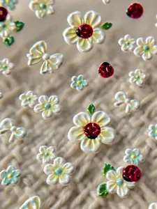 Primer plano detallado de pegatinas de uñas 3D con flores blancas y mariquitas con lazos.