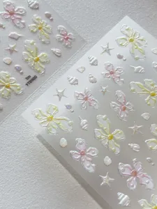 Close-up detail of 3D pearl flower nail art stickers with clear translucent background.