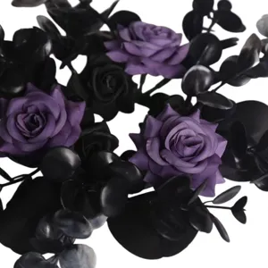 Close-up detail of dark purple artificial roses and black eucalyptus leaves for gothic decor.