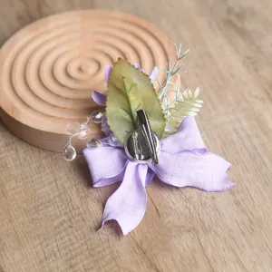 Rückseite Detail der lila Stoff Blumen Korsage mit Metallnadel Clip und Blatt Nahaufnahme.