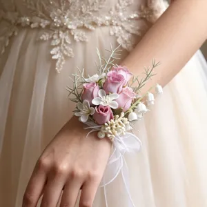 Nahaufnahme eines zarten rosafarbenen Rosen-Handkorsetts mit Perlen und weißer Schleife.