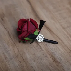 Vue rapprochée de la boutonnière rose bourgogne avec ruban noir et boucle strass scintillante.