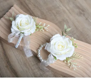 Artificial white rose corsage and wrist flower set with pearls and ribbons for wedding party.