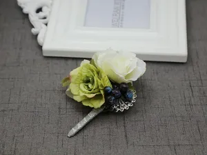 Detailed view of a wedding boutonniere with white rose, green flower, and blue berries.