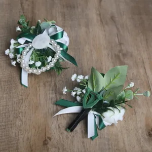 Gros plan de corsage et boutonnière de roses artificielles vert et blanc de style forestier.