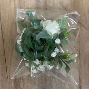 Vue detaillee du corsage de roses artificielles vertes et blanches et de la fleur de poignet.