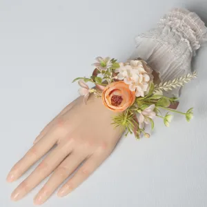 Detailed view of artificial wedding wrist corsage with peach flowers, lace sleeve and ribbons.