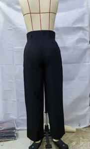 Vista detallada de pantalones casuales negros para hombre expuestos en un maniquí en taller.