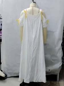 Details van de witte casual maxi-jurk met gele bandjesstrikken en off-shoulder design.