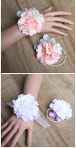 Close up of artificial flower wrist corsage with pearls and ribbons for wedding bride.