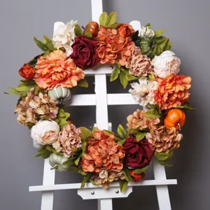 Artificial autumn wreath with pumpkins and flowers for door hanging, harvest decoration.
