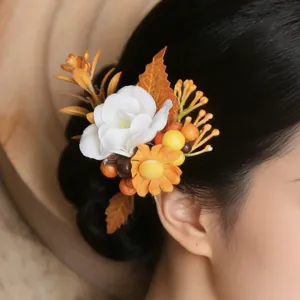 Detail view of forest style floral hair accessory with white flower and orange berries in updo hair.