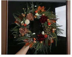 Detalle de corona de flores de otoño artificial con rosas y girasoles para la puerta principal.