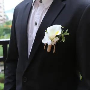 Groom boutonniere detail shot featuring a white calla lily with green leaves and rustic twine wrap.