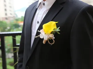 Close-up detail view of the yellow calla lily boutonniere pinned on a black suit jacket.