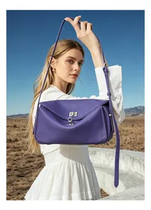 Detail shot of the purple leather shoulder bag outdoors, showing its unique shape and hardware.