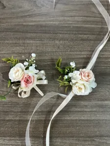 Detail view of artificial rose wrist corsage and boutonniere with ribbons for wedding decor.