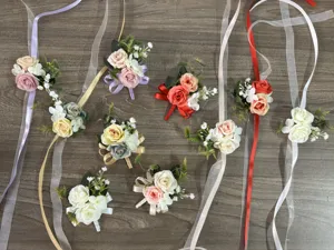 Artificial rose wrist flowers and corsages with long ribbons, detail view of wedding decor.