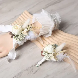 Wedding wrist flower and boutonniere set with artificial white roses and dried natural plants.