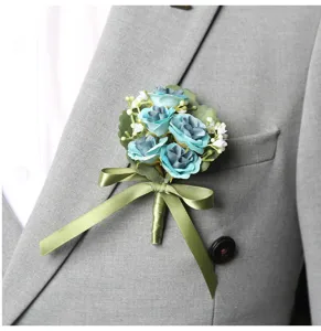 Detailed close-up of blue artificial rose boutonnière with green leaves and ribbon for wedding.