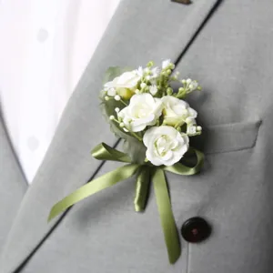 Artificial white rose corsage with green ribbon for wedding groomsman and bridesmaid guest decor.