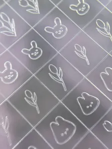 Detailed view of transparent embossed nail stickers featuring cute tulip and rabbit line art designs.