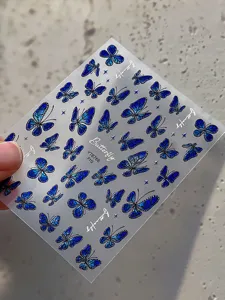 Detail close-up shot of 3D iridescent blue butterfly nail stickers with four-star accents.