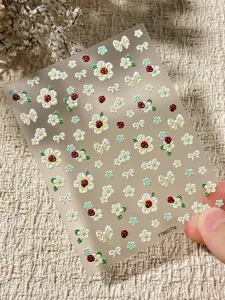 Primer plano de pegatinas de uñas florales 3D con lindas mariquitas y lazos para decoración DIY.