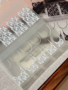 Close-up detail of vintage French lace rose and black white square nail art stickers DIY.