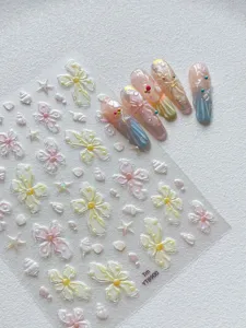 Close-up view of 3D pearlescent butterfly nail stickers with shell and pearl accents.