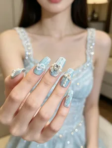 Preciosas uñas postizas azul claro con delicados motivos de encaje, lazos bonitos y brillantes.
