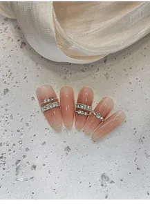 Vista detallada de uñas postizas degradadas nude con cadenas de diamantes de imitación brillantes.