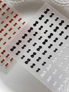 Primer plano de pegatinas de uñas con lazo y lunares 3D, acabado de gel brillante para manicura bonita.