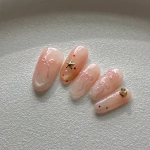 Uñas postizas hechas a mano con lazos rosas en 3D y estrellas doradas, acabado brillante.