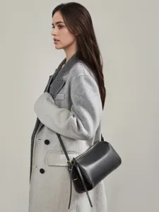 Minimalist black genuine leather cylindrical shoulder bag for women, stylish daily crossbody.