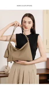 Primo piano di una borsa a spalla minimalista in pelle con ciondolo e tracolla regolabile.