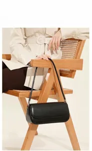 Detail zwarte lederen schoudertas, minimalistische baguette-stijl met metalen beslag.