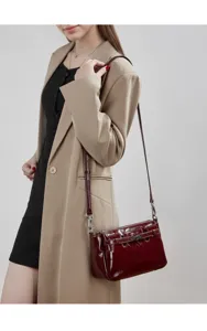 Detailed view of the elegant burgundy patent leather shoulder bag worn with a chic beige blazer.