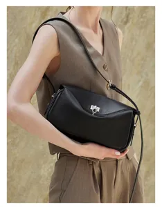 Detailed view of stylish black leather messenger bag worn on shoulder with metal lock.