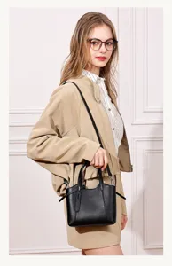 Detailed shot of a sleek black leather tote bag worn on shoulder, showcasing minimalist design.