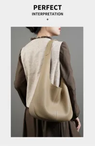 Gedetailleerd overzicht van een minimalistische beige lederen schoudertas gedragen door het model.