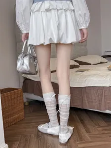 Detailed shot of sheer striped knee-high socks with cute bowknot design in a chic bedroom scene.