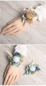 Detailed view of artificial rose wrist corsage and boutonniere set for wedding decoration.